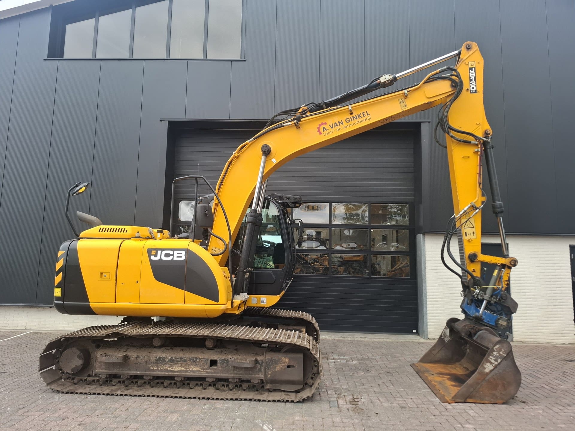 Zijaanzicht van de JCB JS130LC met SMP ST15 draai-kantelstuk en bak