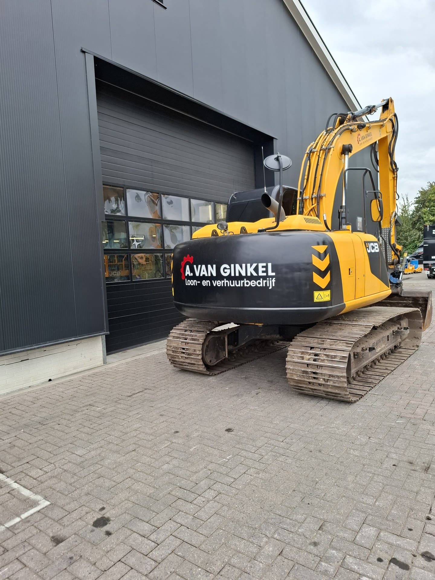 Achteraanzicht van de JCB JS130LC met belettering van A. van Ginkel Loon- en verhuurbedrijf